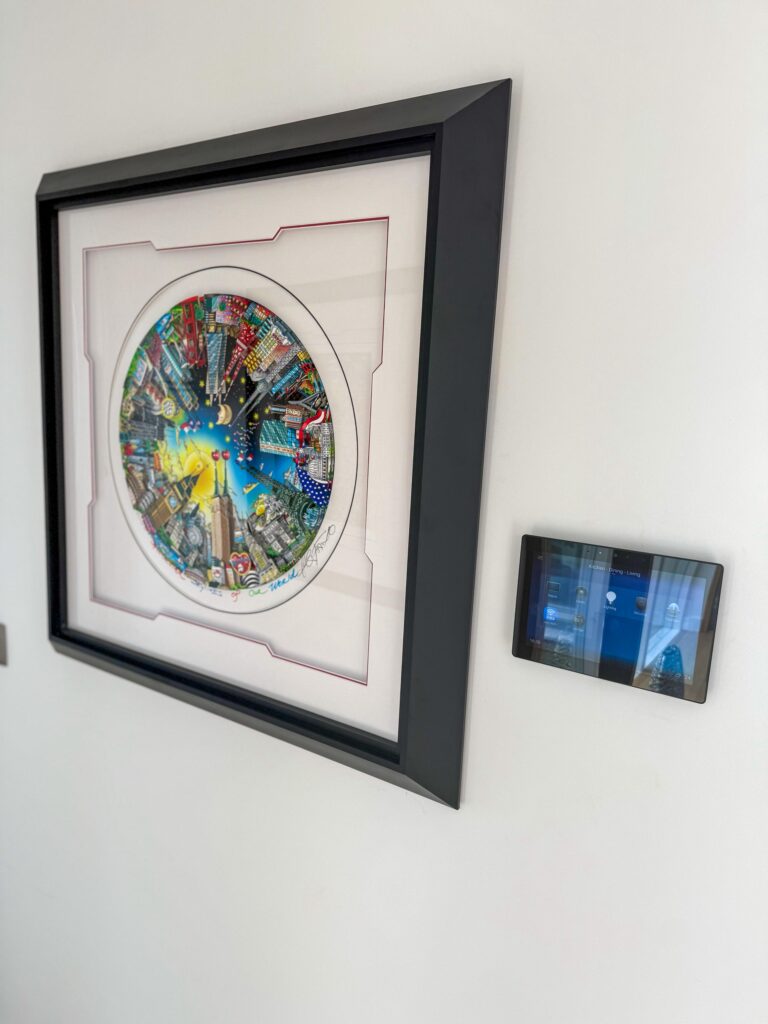 Control4 wall touchscreen beside framed artwork