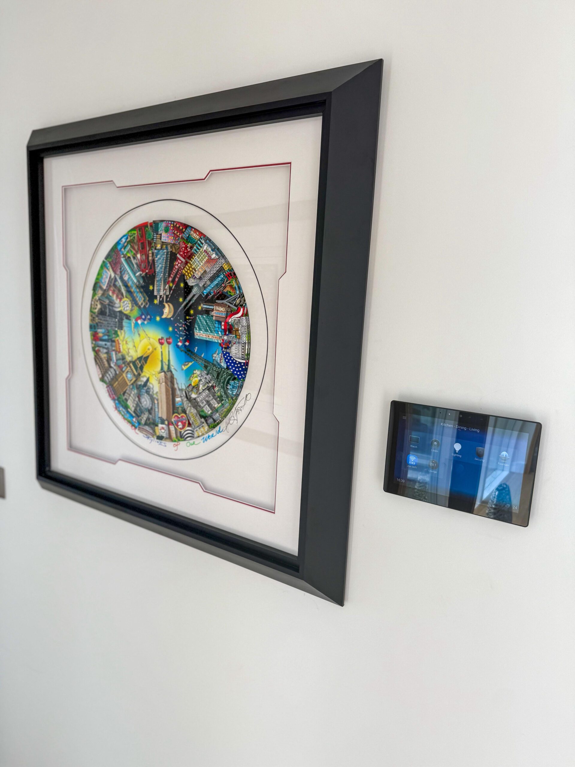 Control4 wall touchscreen beside framed artwork